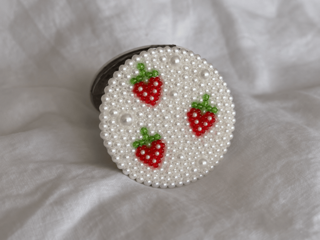 Pink compact mirror decorated with pearls and colorful rhinestones, a cute bedazzled DIY craft idea for girls night or personalized gifts.